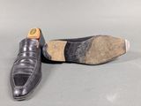 pair of men ' s black leather shoes on a grey surface