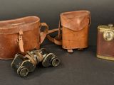 two old leather bags and a pair of binoculars on a black background
