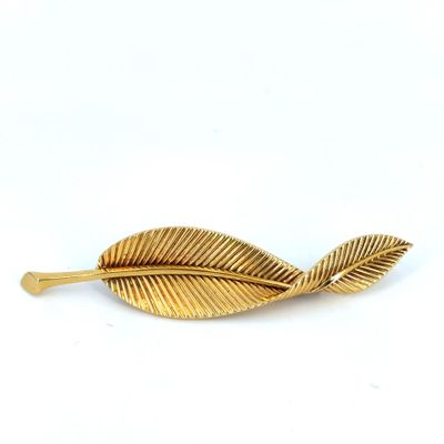 a close up of a gold leaf brooch on a white background