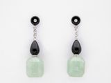 une paire de boucles d'oreilles noires et blanches ornées de perles de verre vertes