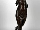 une statue antique en bronze représentant une femme tenant un oiseau