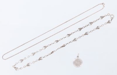 trois colliers en argent et un pendentif en argent sur fond blanc