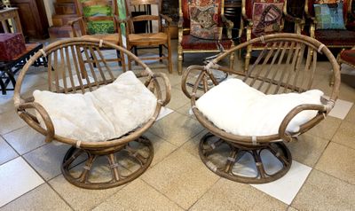pair of rattan chairs with white cushions in a store