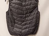 the back of a black puffy vest hanging on a white wall