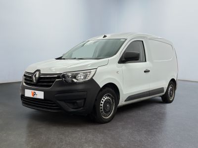 La camionnette blanche est garée dans une grande pièce au sol noir.