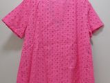 a pink shirt hanging on a hanger against a wall