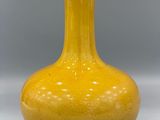 a yellow vase sitting on a table with a gray background