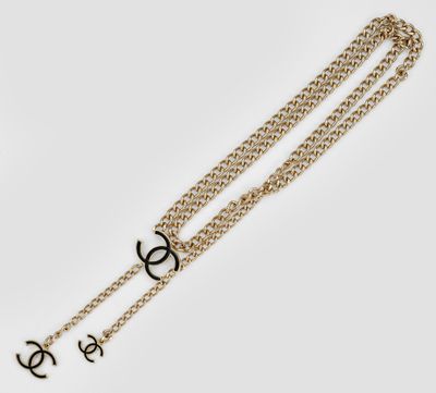 un bracelet en chaîne dorée orné d'un logo noir et blanc