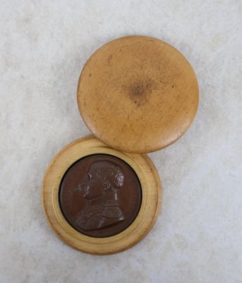 une boîte en bois contenant une pièce de monnaie, posée sur une surface blanche