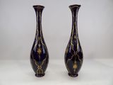 une paire de vases noirs et dorés posés sur une surface blanche