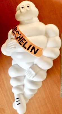 a white figurine of a man with a ribbon around his neck