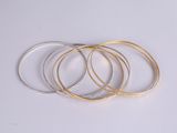 a close up of a stack of gold bangles on a white surface