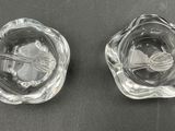two glass ashtrays on a table with a spoon and spoon in the middle