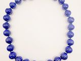 a close up of a necklace with blue beads on a white surface