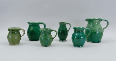 several green vases are lined up in a row on a white surface