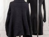 two black sweaters on a stand in front of a white wall