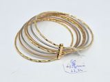 four gold and silver bang bracelets on a white surface
