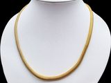 un collier en or sur un mannequin blanc, sur fond noir