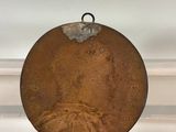 an old metal plate with a picture of a woman on it