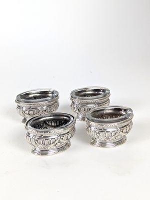 quatre bols en métal argenté, ornés de motifs sur un fond blanc