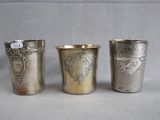 three silver cups with designs on them sitting on a table