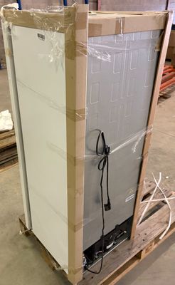 un réfrigérateur blanc posé sur une palette dans un entrepôt