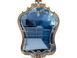 une image représentant un miroir doré avec un canapé bleu en arrière-plan