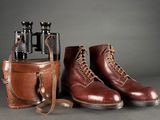 pair of red wing boots and a case with binoculars on a gray background