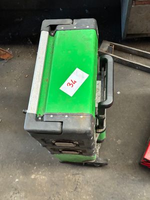 une machine verte posée par terre à côté d'une boîte rouge