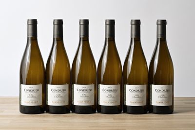 six bottles of white wine lined up on a wooden table
