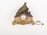 une horloge surmontée d'une statue, à côté d'une paire de ciseaux