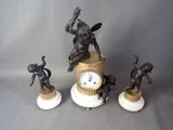 une horloge et trois figurines posées sur une table