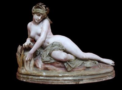 marble statue of a woman laying on a rock with a bird in her hand