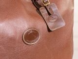 a brown leather bag with a tag on it