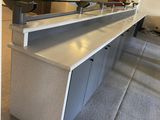 a counter with a sink and a refrigerator in the room