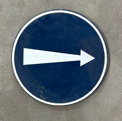 un panneau bleu et blanc sur lequel figure une flèche