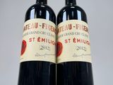 two bottles of red wine sitting next to each other on a table