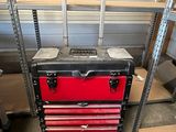 a red and black tool box with wheels in a garage