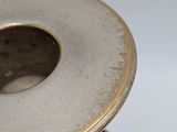a silver candle holder with a gold rim on a table