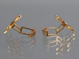 pair of gold plated cufflinks on a reflective surface