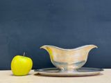 a silver gravy dish and an apple on a plate