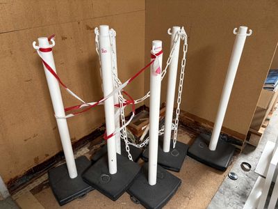 four white poles with chains on them in the corner of a room