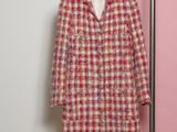 a pink and white coat hanging on a hanger in front of a pink wall