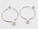 boucles d'oreilles en anneau en argent ornées de perles blanches, posées sur un fond blanc