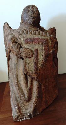 statue d'un homme assis sur une table en bois, avec un mur blanc en arrière-plan