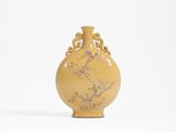 un vase jaune posé sur une surface blanche, sur fond blanc