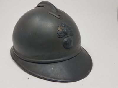 Un vieux casque est posé sur une table devant un fond blanc.