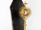 un coffret doré et noir surmonté d'une croix