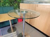 une table avec un plateau en verre et une chaise placée devant un mur vert