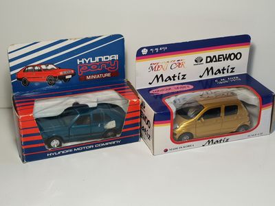 two boxes of toy cars sitting on top of a white surface